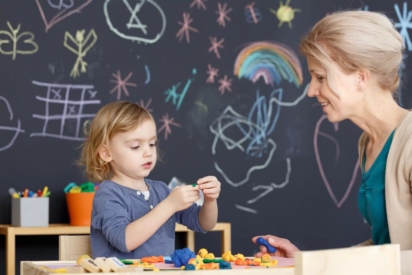 Pedagogisch professional knutselt met een peuter aan tafel